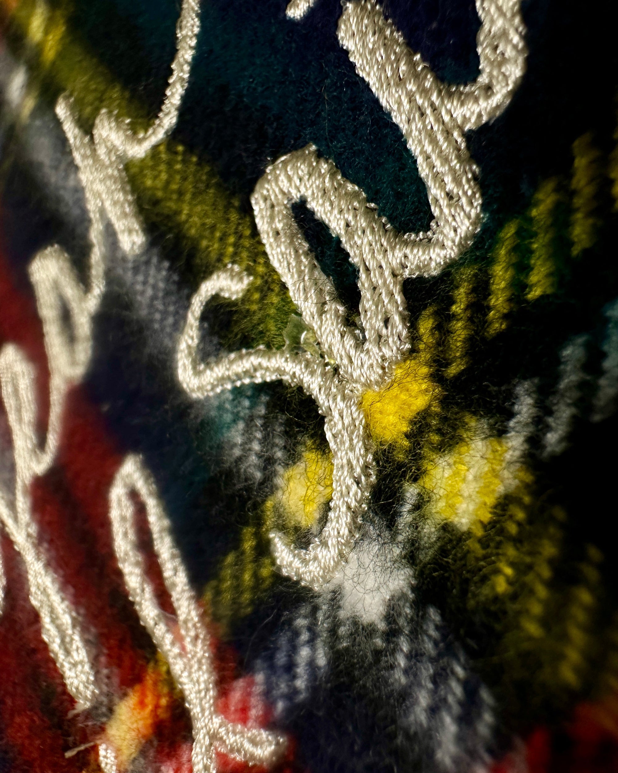 Close-up of embroidered text on a multicolored fabric background